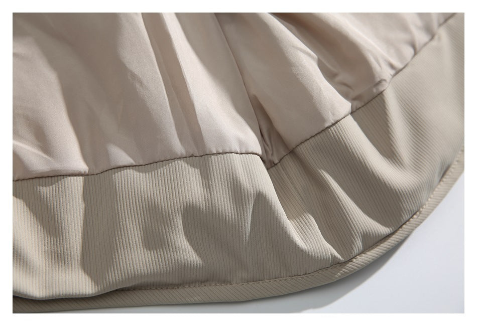 Close-up of the beige jacket's curved lower hem, showing ribbed outer fabric and smooth lining.