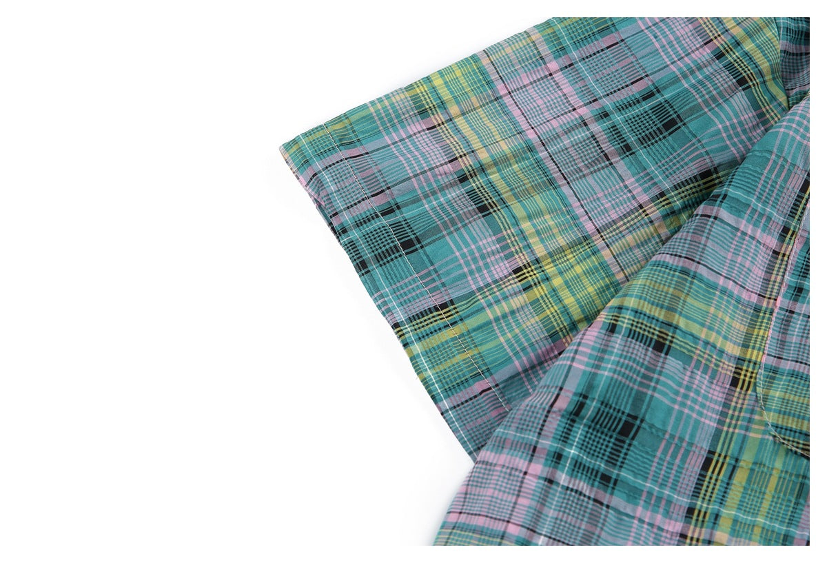 Close-up of a short sleeve showing the shirt's teal, pink, yellow and black plaid pattern.