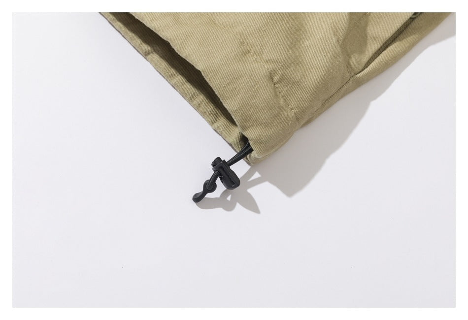 Close-up of a tan jacket hem with a black adjustable drawcord toggle.