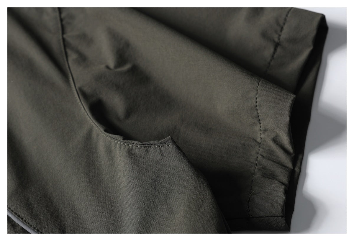 Close-up of olive-gray shirt fabric, stitching, and a folded edge near a seam.