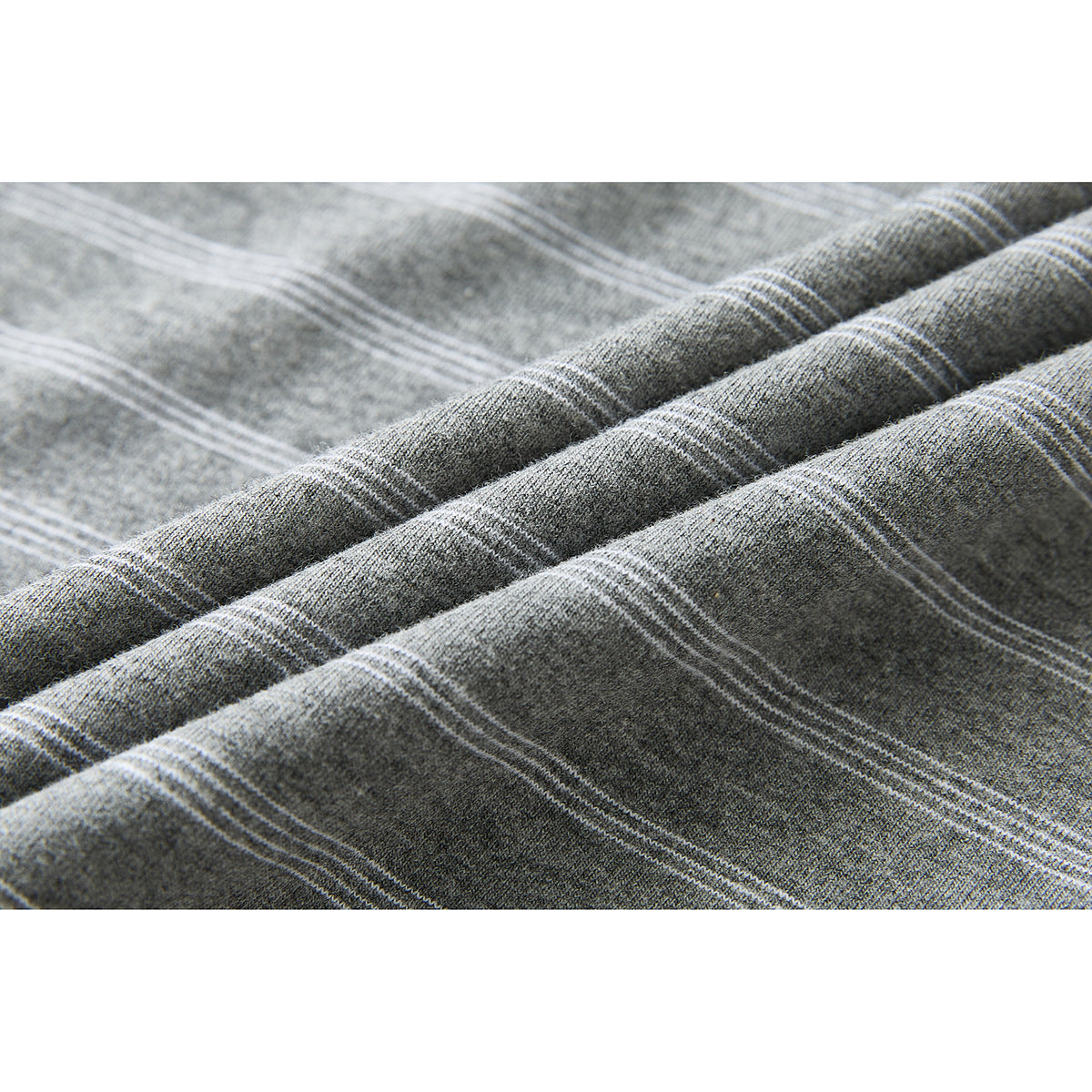 Close-up of gray knit fabric with narrow white horizontal stripes, shown folded in soft ridges.