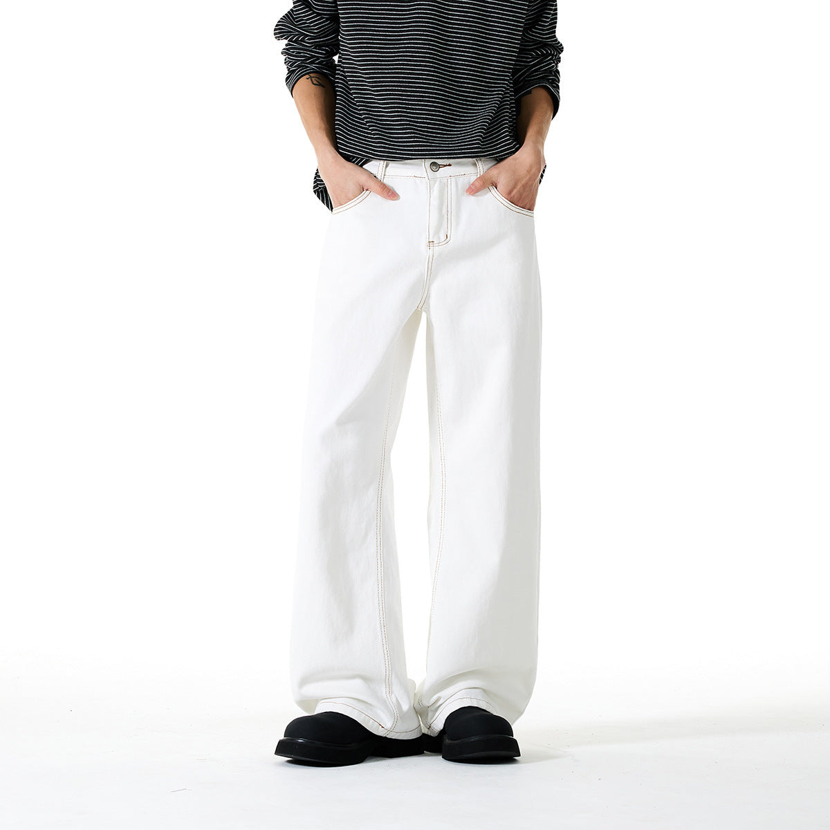 Front view of white wide-leg pants with contrast stitching, worn with a black striped top and black shoes.