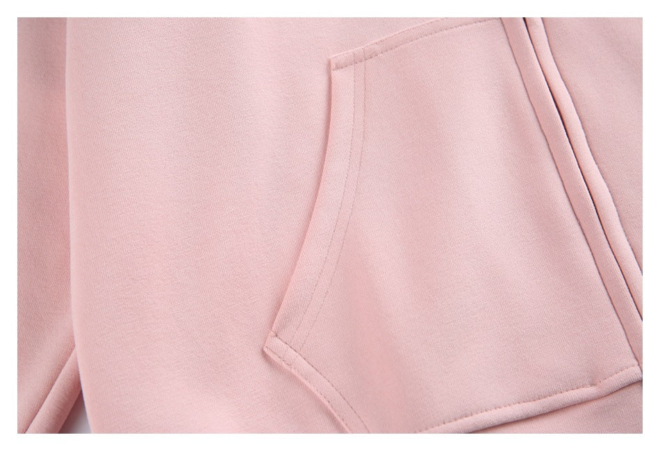Close-up of a pocket opening and stitching on pale pink hoodie fabric.