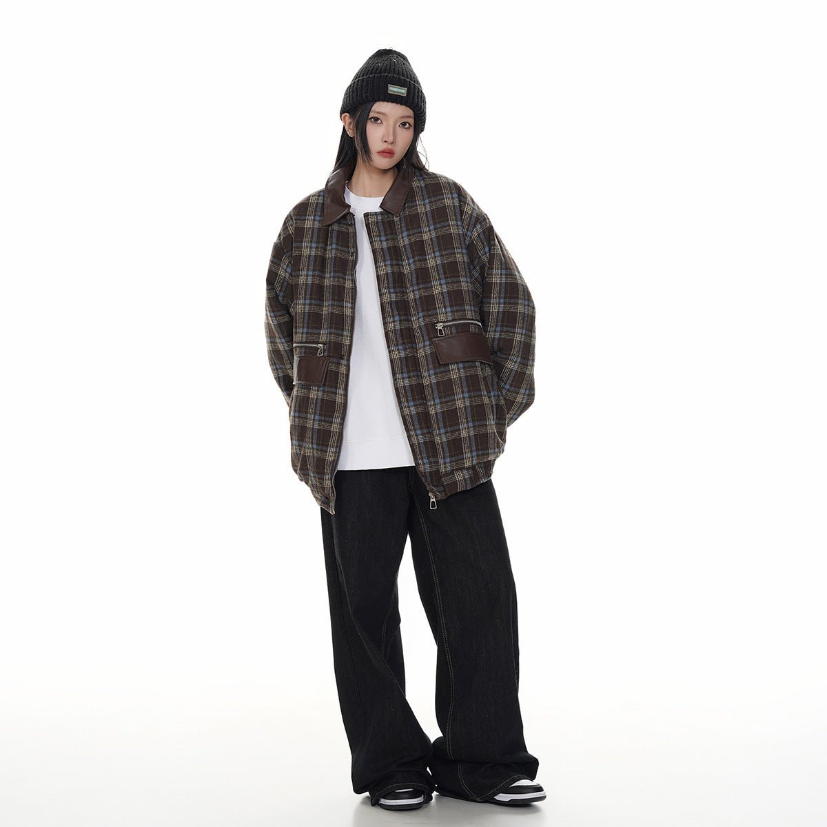 Full-length front view of a model in a brown plaid jacket with a dark collar and zip pockets, black beanie, and wide-leg