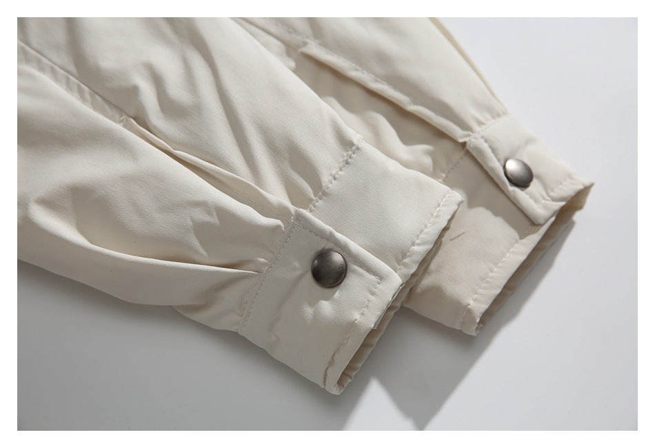 Close-up of an ivory garment's sleeve cuffs with stitching and silver snap buttons.