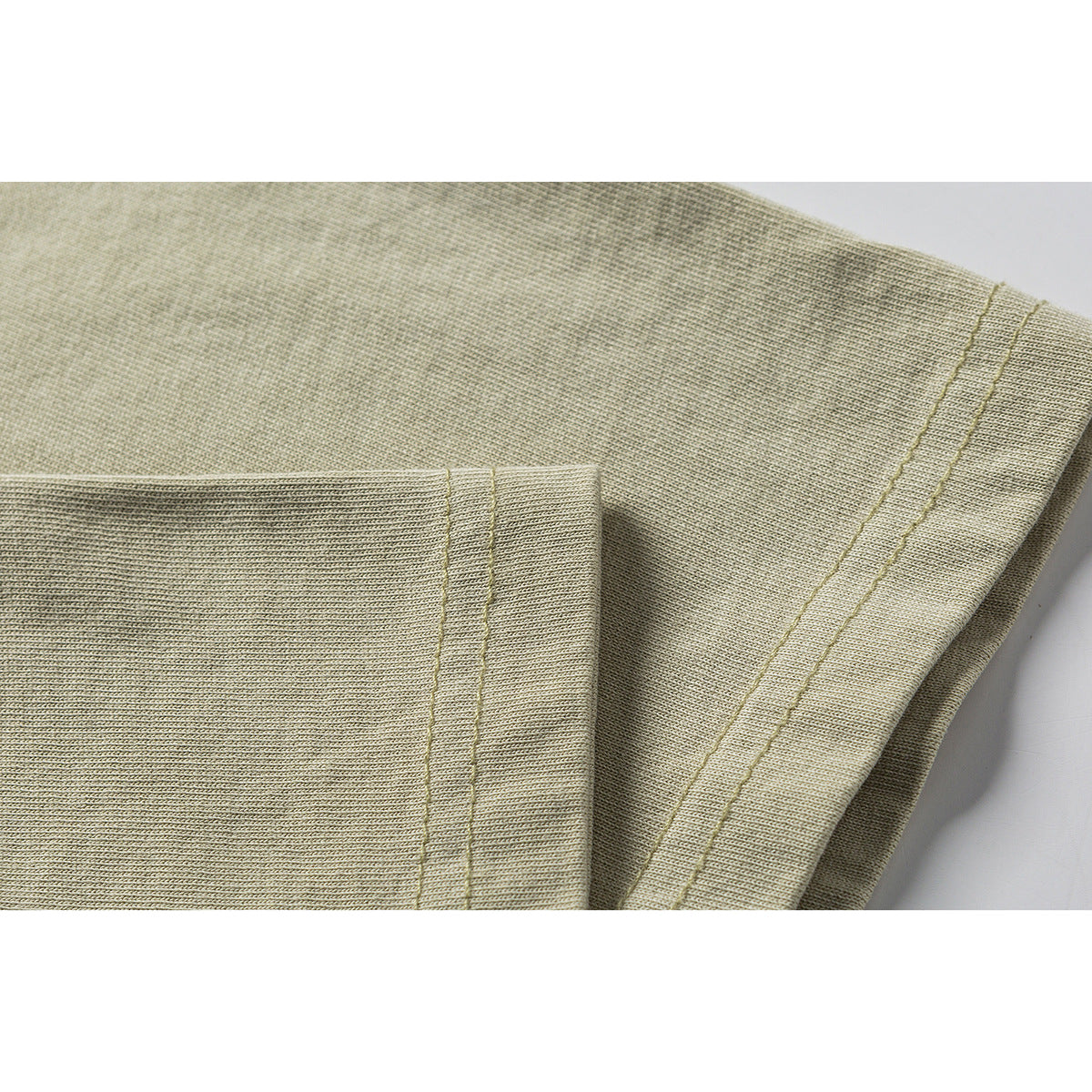 Close-up of a beige T-shirt sleeve and double-stitched hem.
