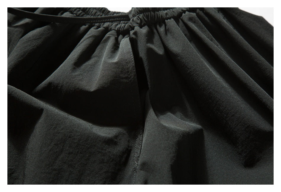 Close-up of a black garment's elastic waistband, drawstring, and stitched front panel.