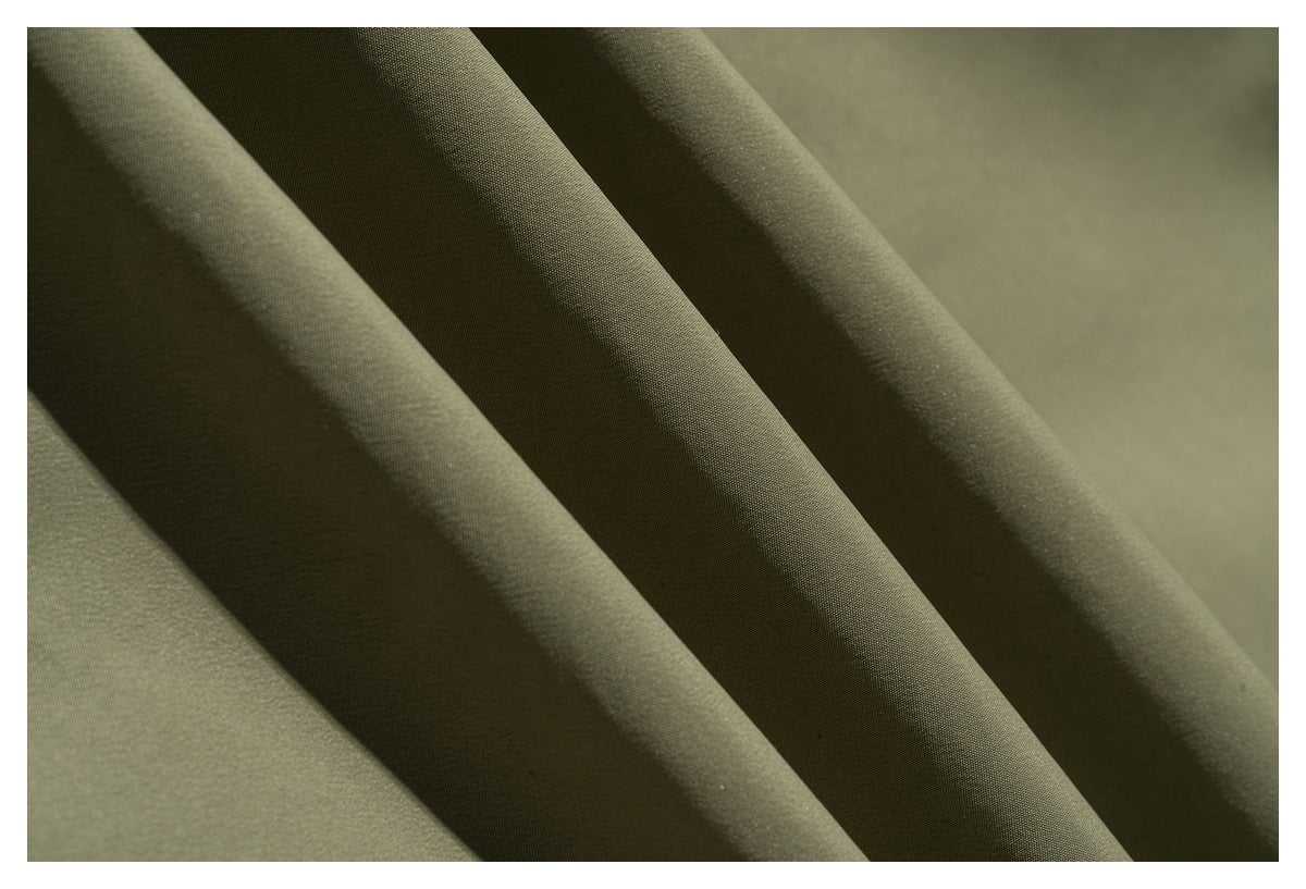 Close-up of olive-green fabric arranged in soft folds, showing its surface texture.
