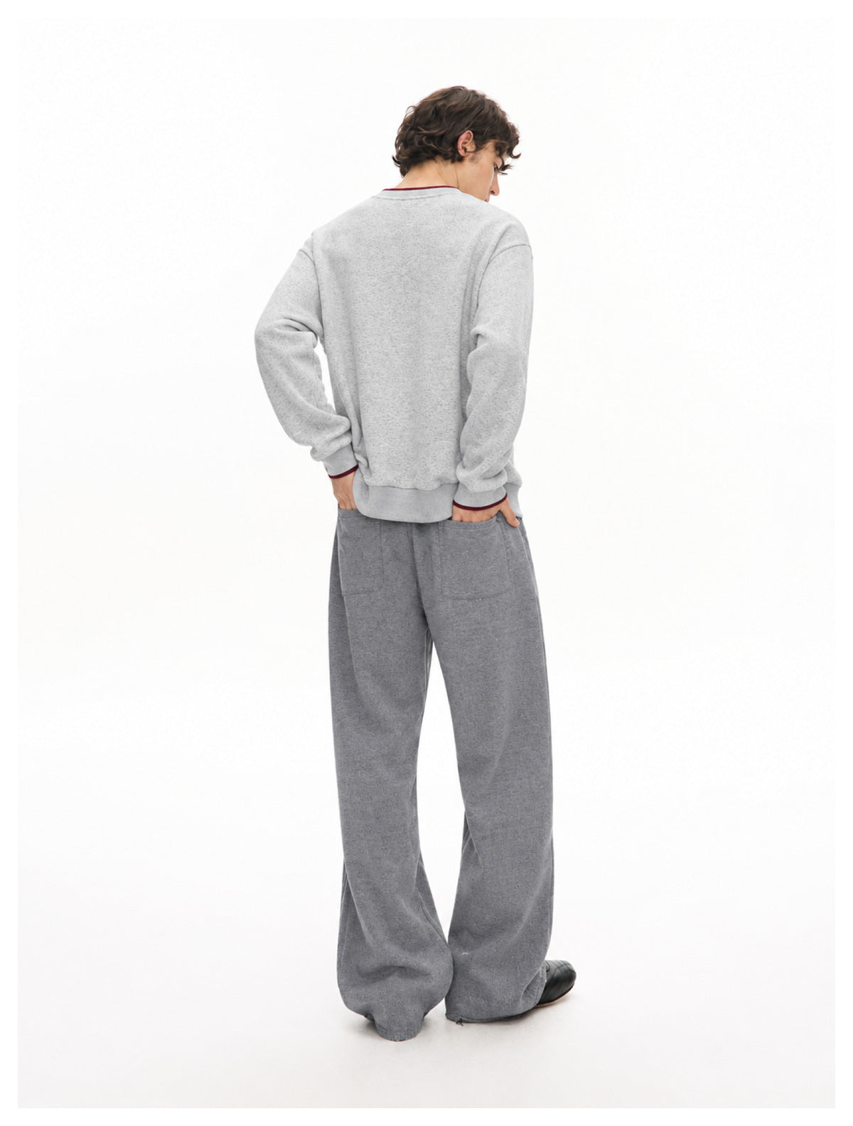 Rear view of a model wearing a light gray sweatshirt and wide-leg dark gray pants with back pockets.