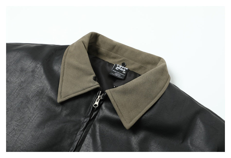 Close-up of a black jacket with a contrasting taupe pointed collar, front zipper, and neck label.