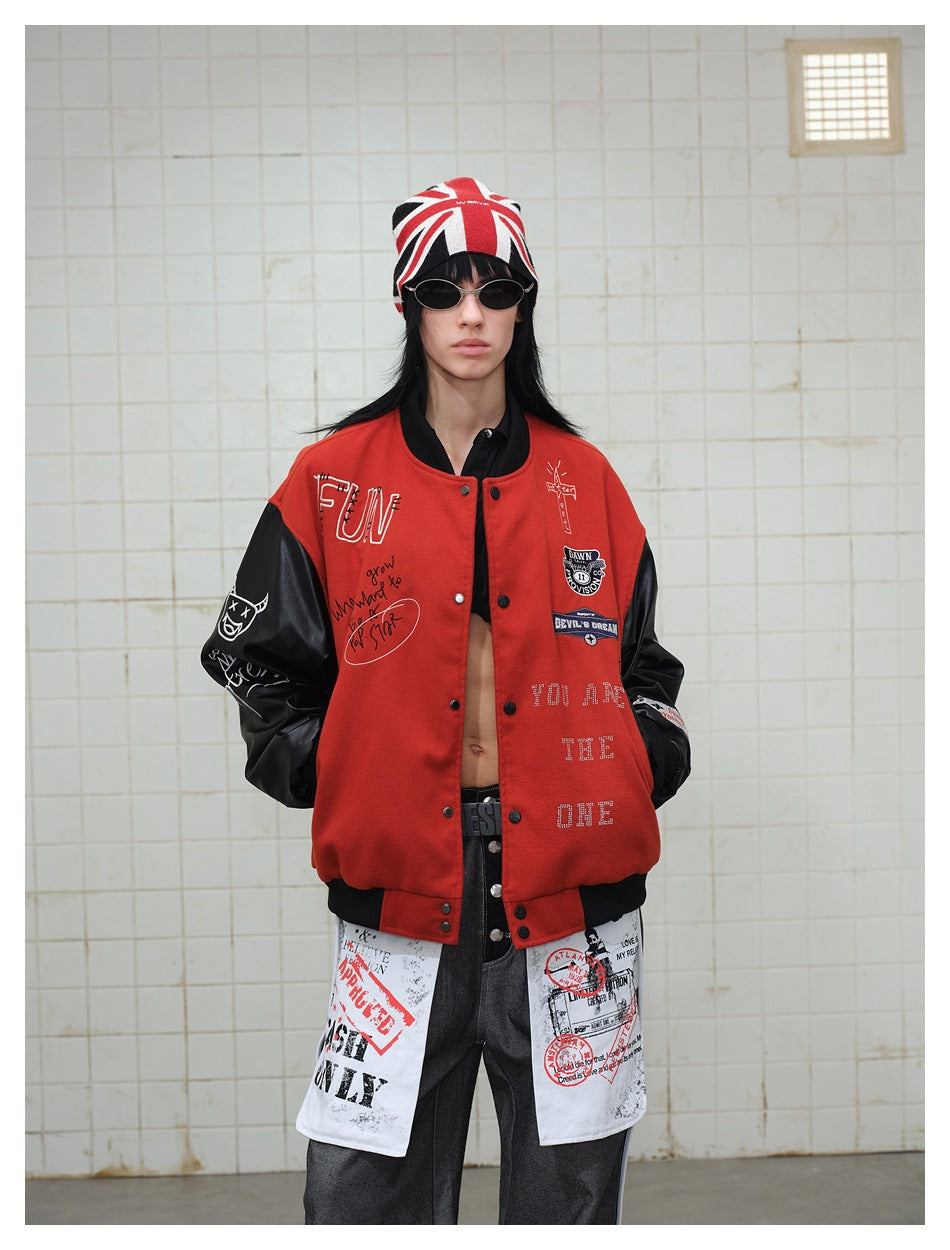 Model wearing a red-and-black graphic varsity jacket with a Union Jack beanie and layered graphic panels over dark trousers.
