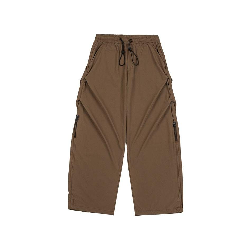 Brown wide-leg pants with elastic drawstring waist, side pleats and cord toggle details, flat lay front view
