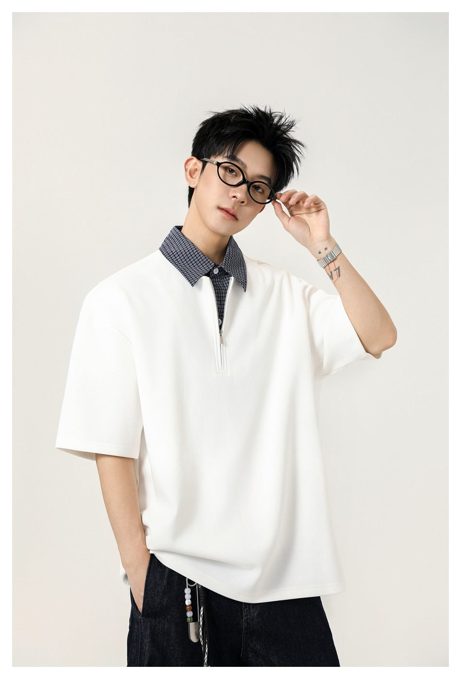 Close view of a model wearing a white quarter-zip polo with a checked collar and short sleeves.