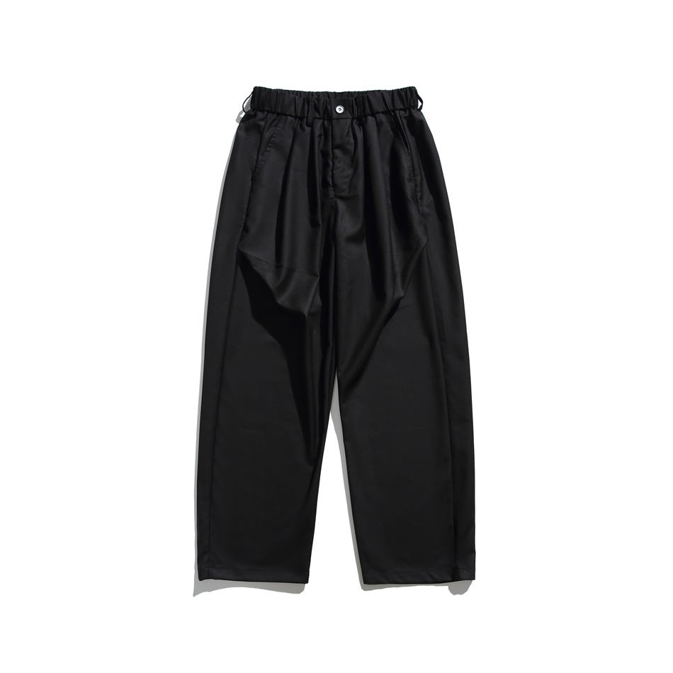 Black wide-leg trousers with elastic waistband, front button and pleats, flat lay front view