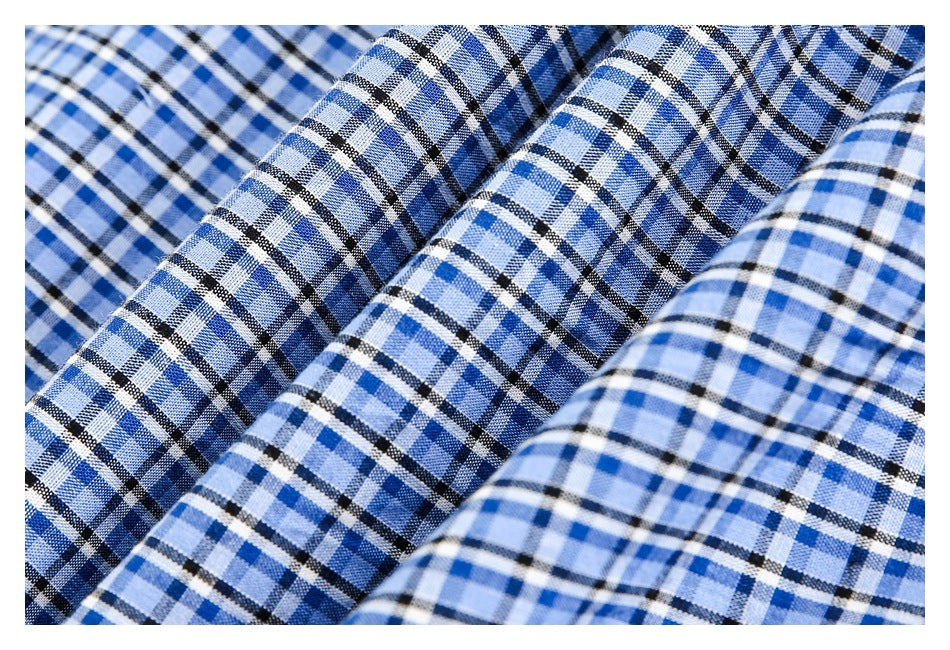 Close-up of blue plaid fabric gathered into folds, showing its woven pattern and texture.