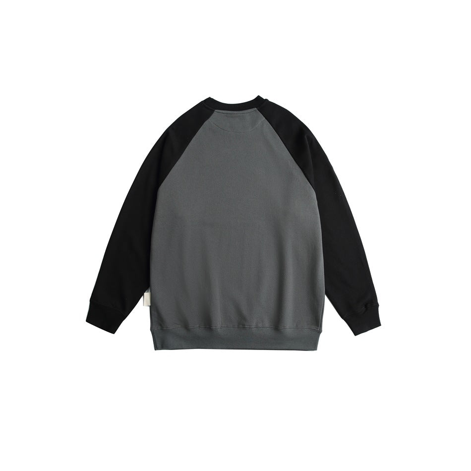 Back view of a gray raglan sweatshirt with black sleeves, ribbed crew neck, cuffs and hem, laid flat on white.