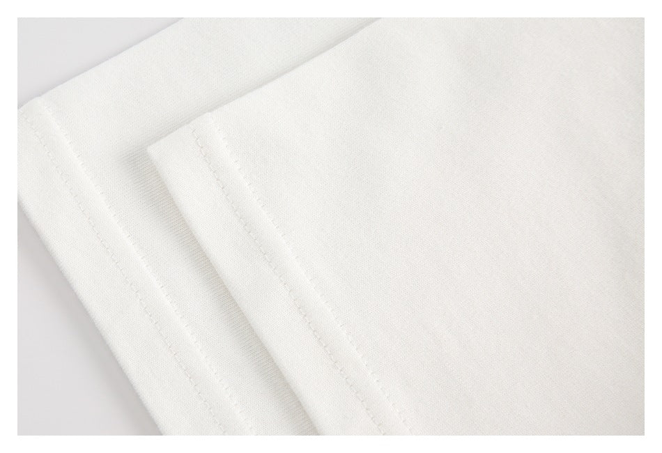 Close-up of white garment fabric with overlapping folded edges and straight stitching.
