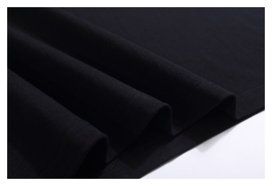 Close-up of black T-shirt fabric arranged in soft folds, with the hem stitching visible.