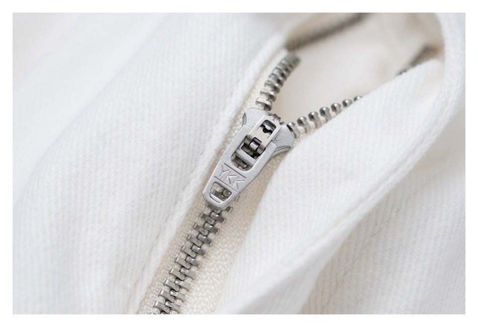Close-up of a silver zipper on white trousers; the zipper pull is stamped YKK.