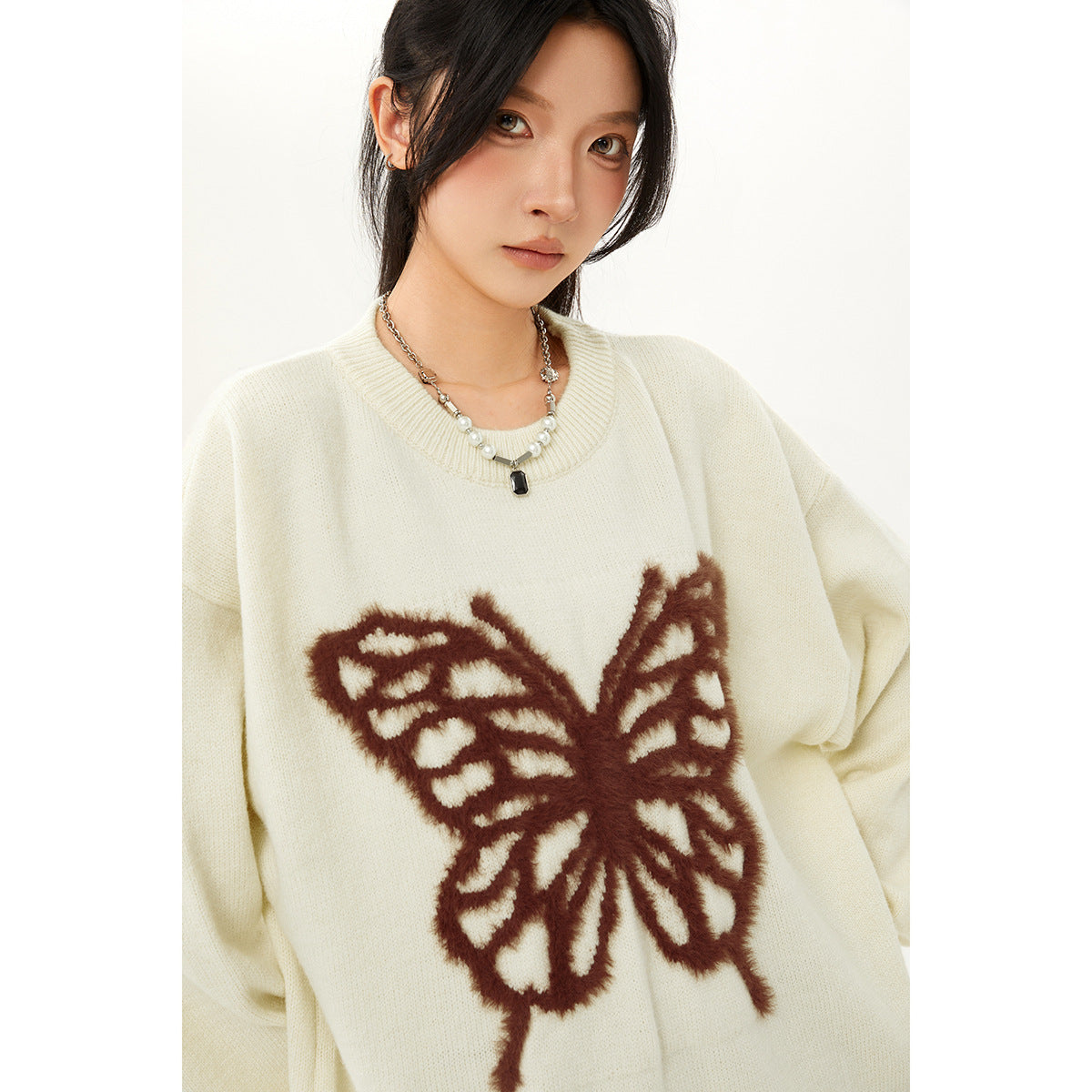 Close view of a model wearing an ivory oversized sweater with a large brown butterfly design.