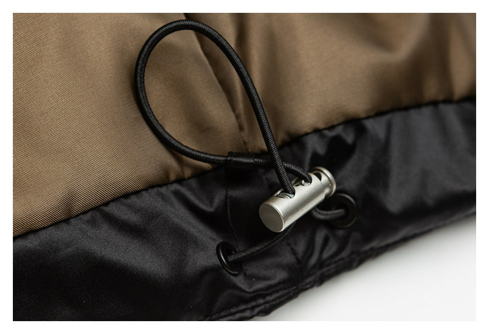 Close-up of a black drawcord toggle at the seam between brown and black garment panels.