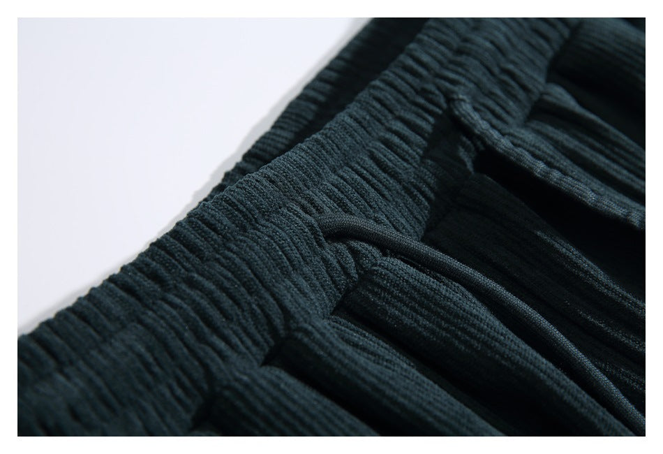 Close-up showing the gathered elastic waistband and drawstring channel on the dark teal pants.