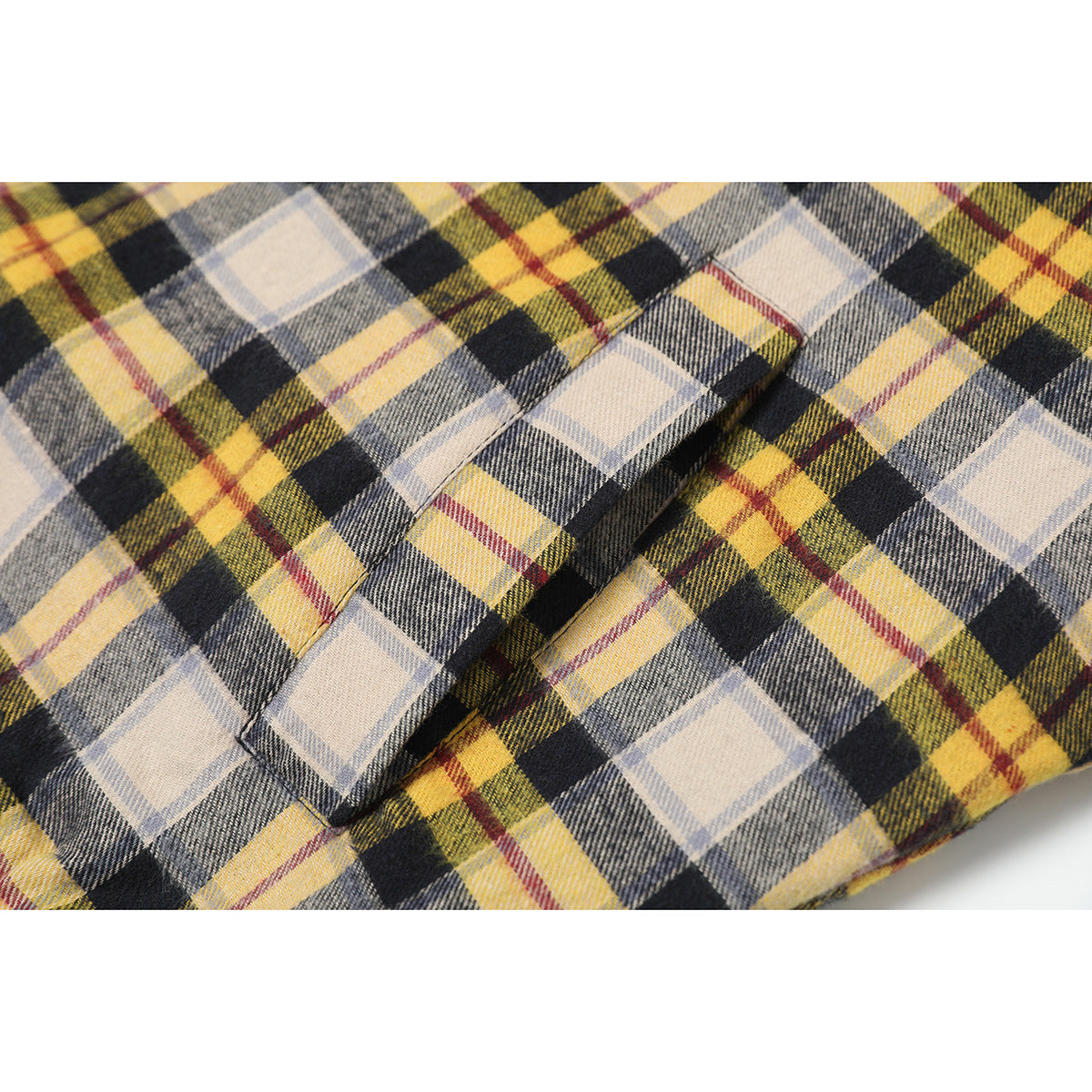 Close-up of yellow, gray, cream, and black plaid fabric with a stitched seam and folded edge.