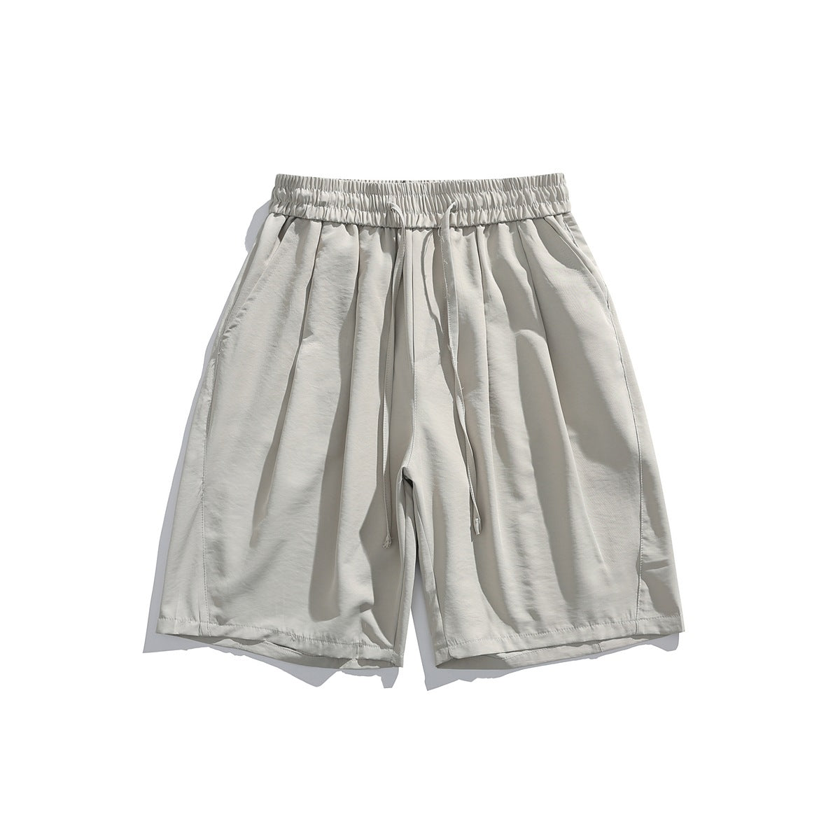 Front view of loose light beige shorts with an elastic drawstring waist and side pockets.