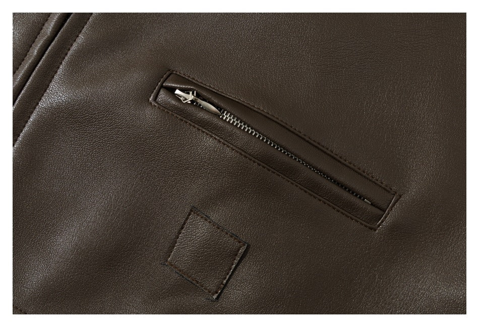Close-up of a dark brown garment with a diagonal metal zipper pocket and a small square stitched patch.