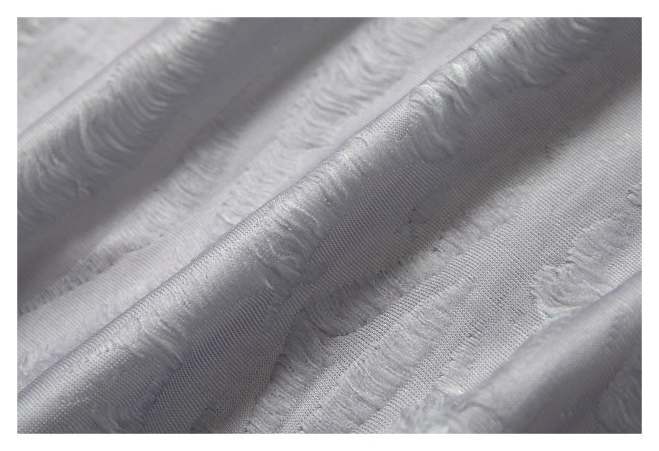 Macro view of raised wavy stripes and smooth bands on white fabric.