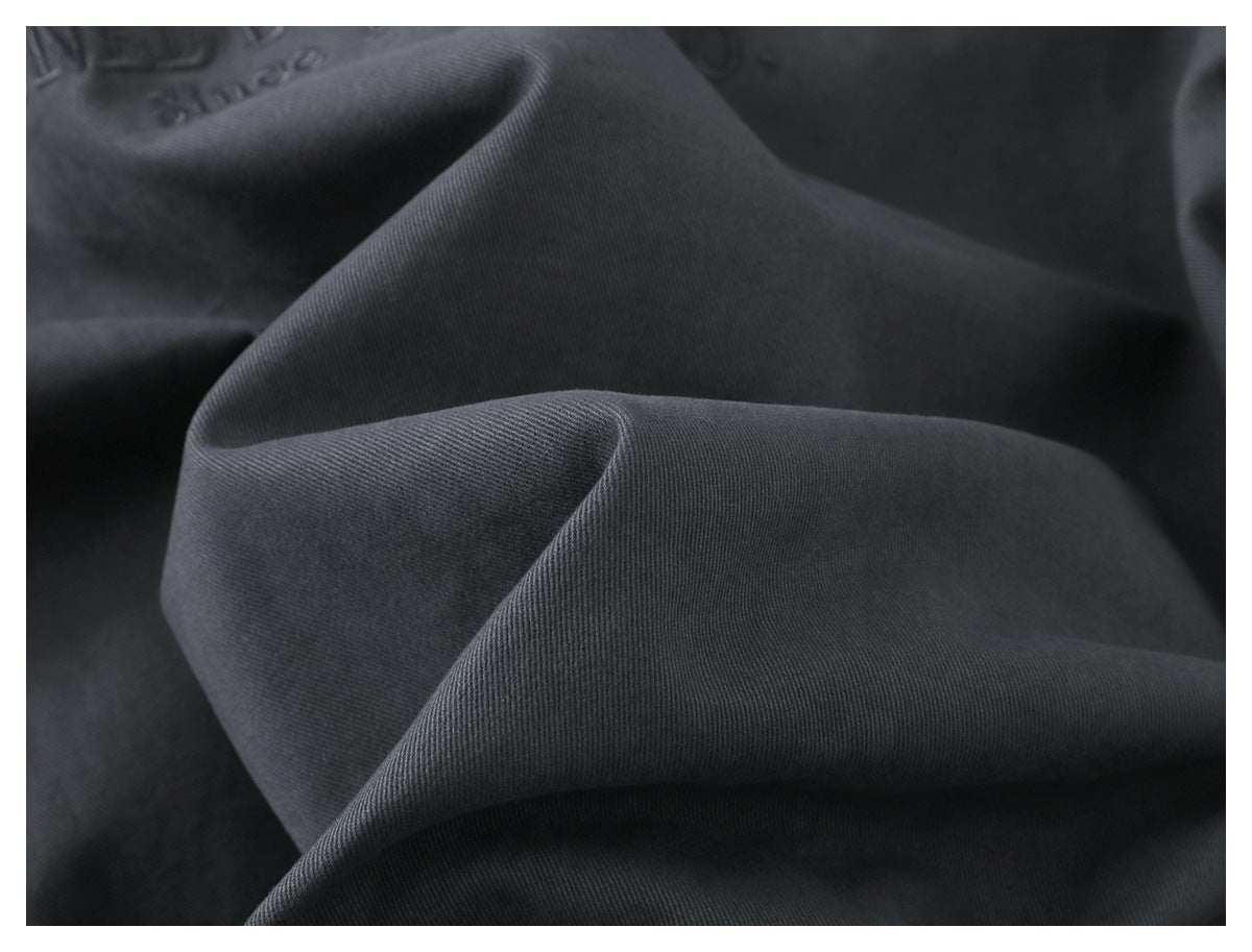 Close-up of dark charcoal fabric draped in folds, showing its fine diagonal texture.