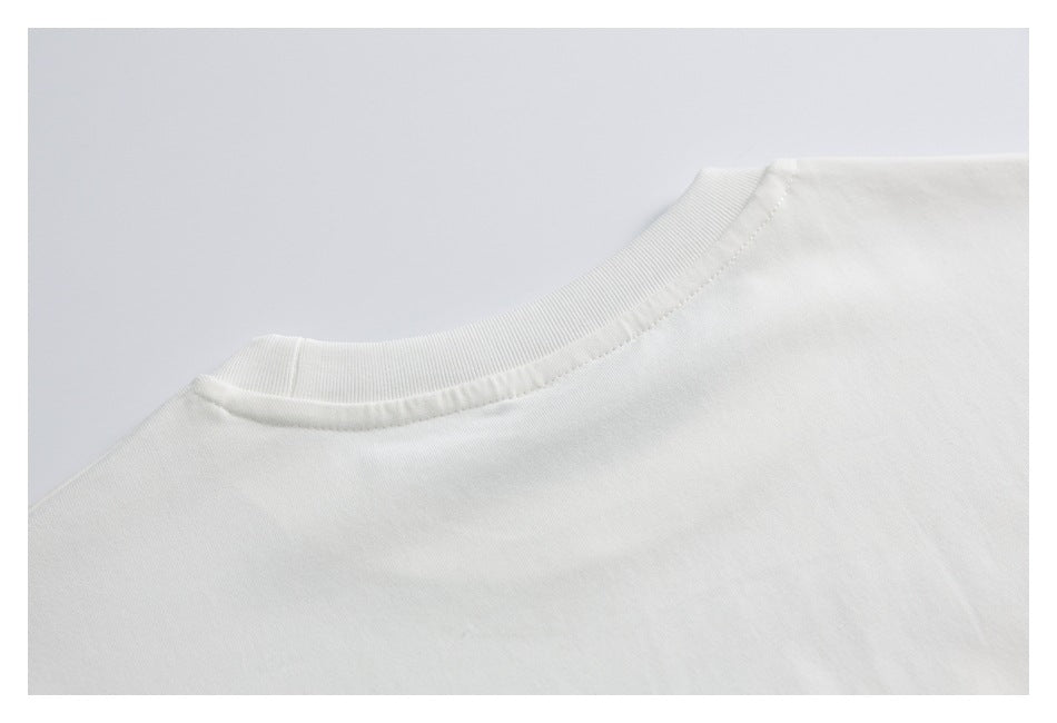 Close-up of the ribbed crew neckline and shoulder seam on a white T-shirt.