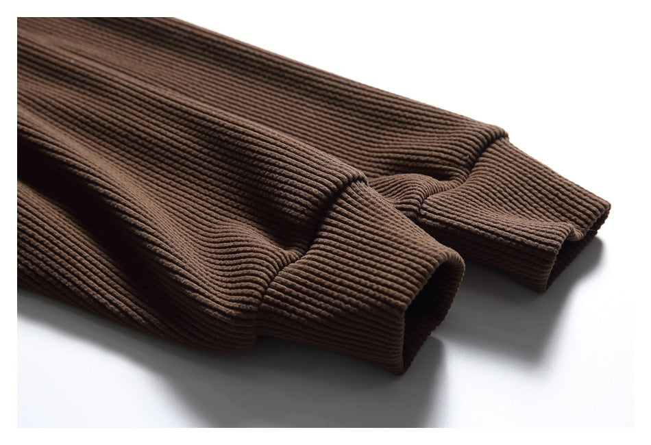 Close-up of brown ribbed sweatshirt sleeve cuffs and textured knit fabric.