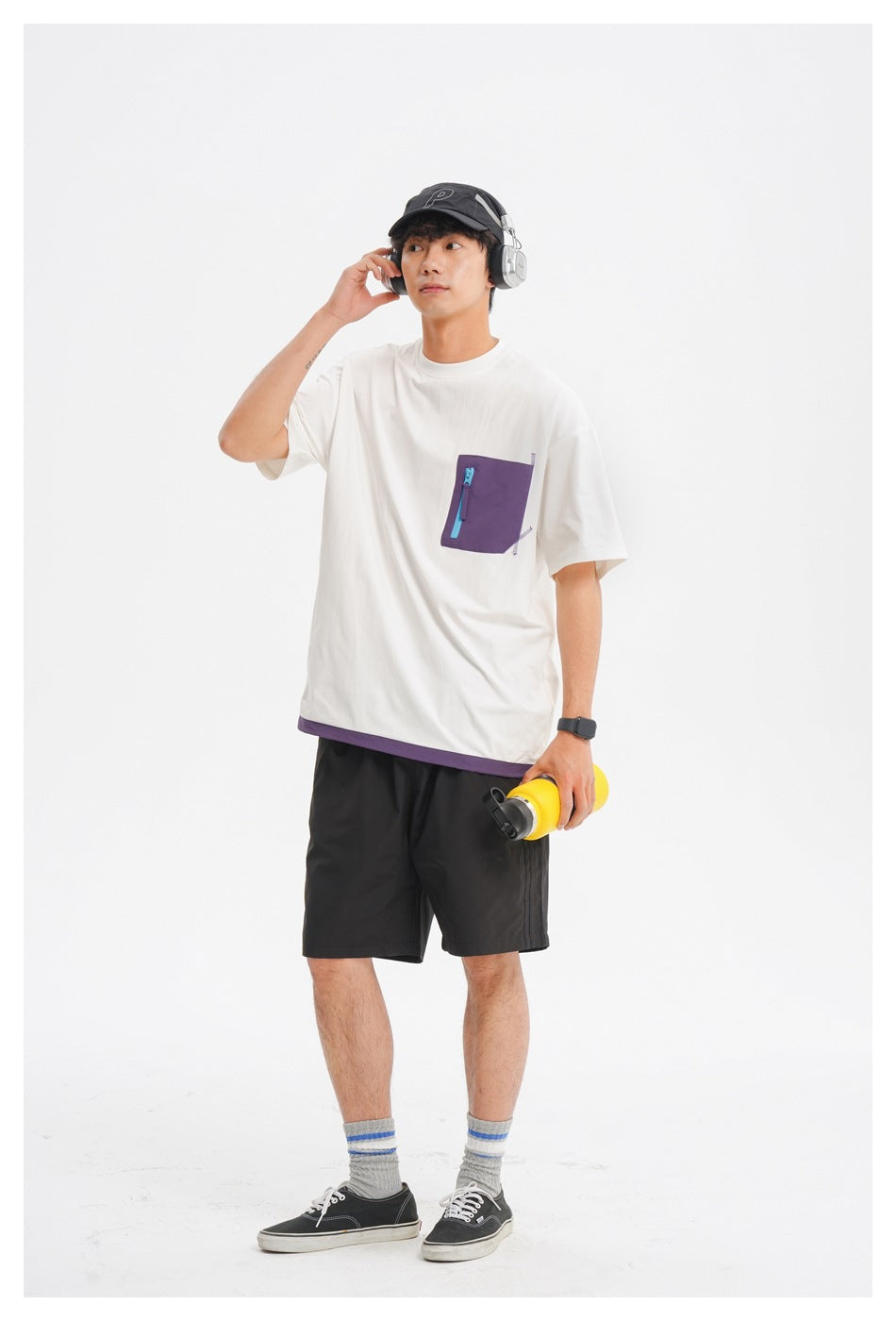 Front view of a model in an oversized white tee with a purple zip chest pocket and purple hem trim.