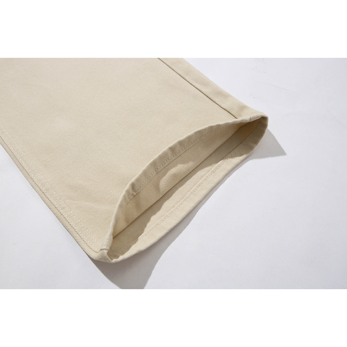 Close-up of the stitched hem on a beige pant leg, showing the folded edge and fabric texture.
