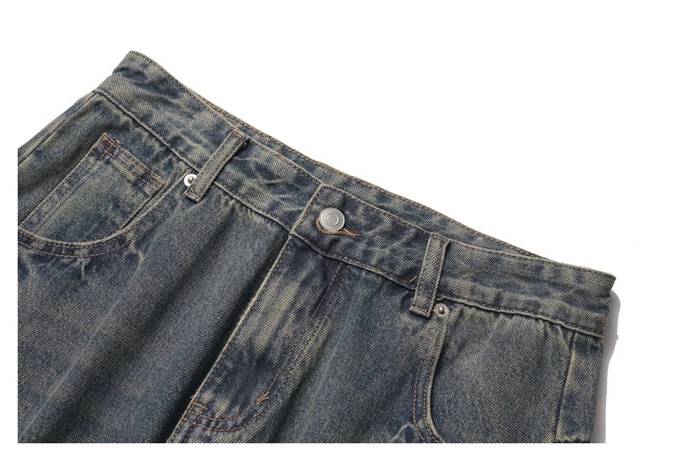 Close-up of the front waistband and pockets of faded dark blue jeans with a metal button and belt loops.