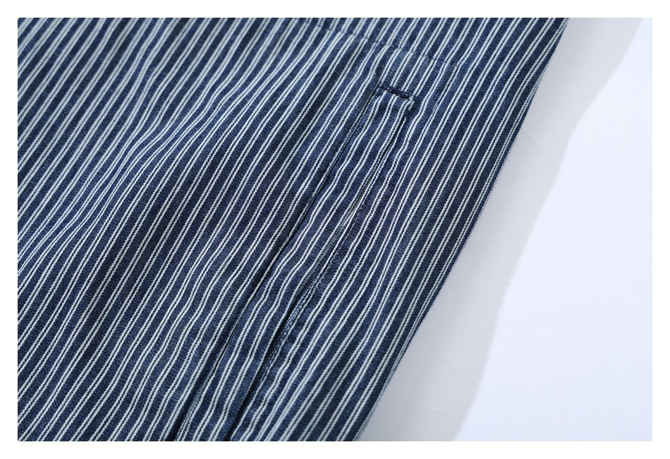 Close-up of navy fabric with narrow white pinstripes and a stitched pocket opening.