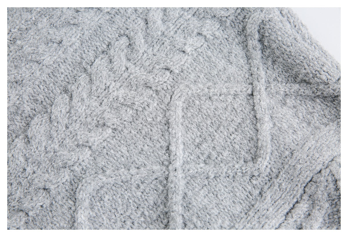 Close-up of light gray knit fabric with raised cable-like stitches and a textured surface.