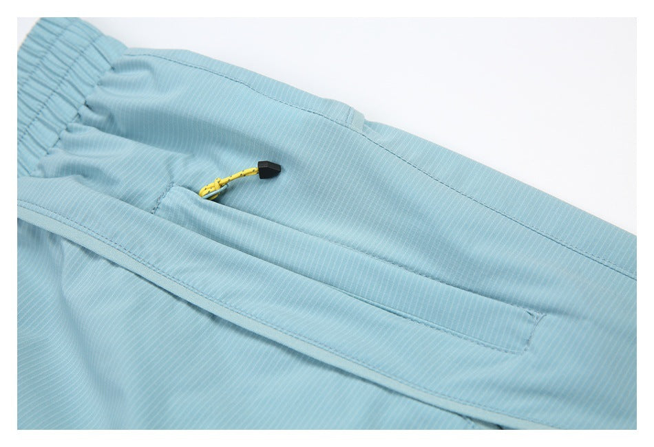 Close-up of a zip pocket and yellow cord pull on light blue striped bottoms.