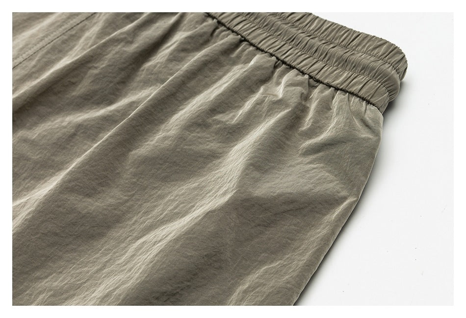 Close-up of the gray-green shorts' elastic waistband and gathered side fabric.