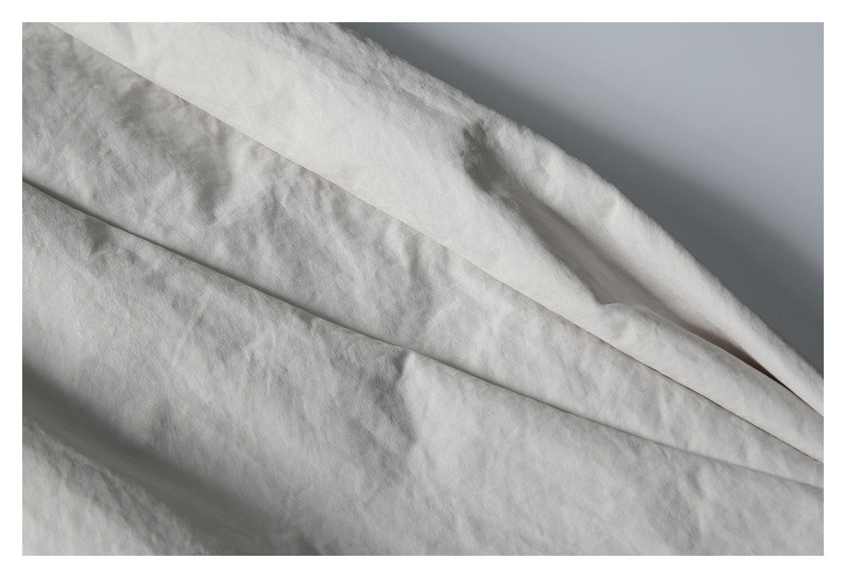 Close-up of the light gray shorts fabric, showing its softly crinkled texture and stitched panel seam.