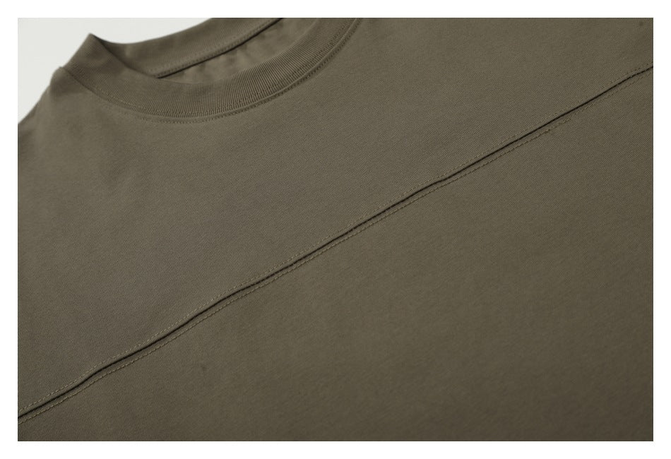 Close-up of the olive-brown T-shirt's neckline and diagonal stitched chest seam.