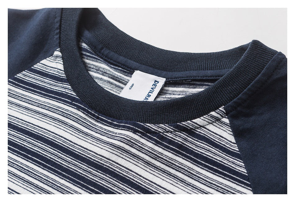 Close-up of a navy ribbed crew neckline and striped chest on a T-shirt, with the neck label visible.