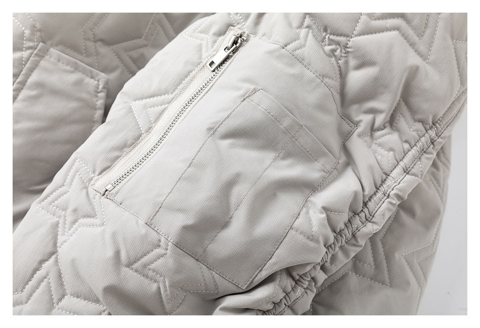 Close-up of a light gray star-quilted jacket showing a zippered pocket and gathered edge.