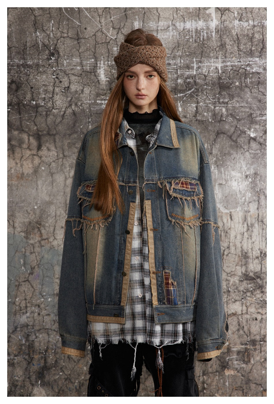 Front view of a model wearing an oversized blue denim jacket with distressed plaid-trimmed pockets and patchwork.