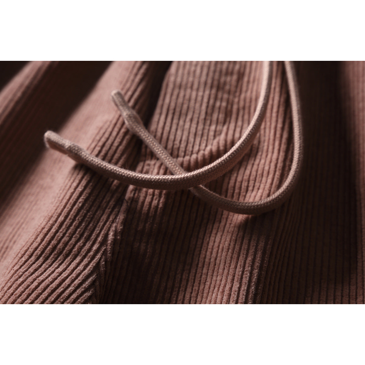 Close-up of the braided drawstring and fine vertical ribbing on dusty rose pants.