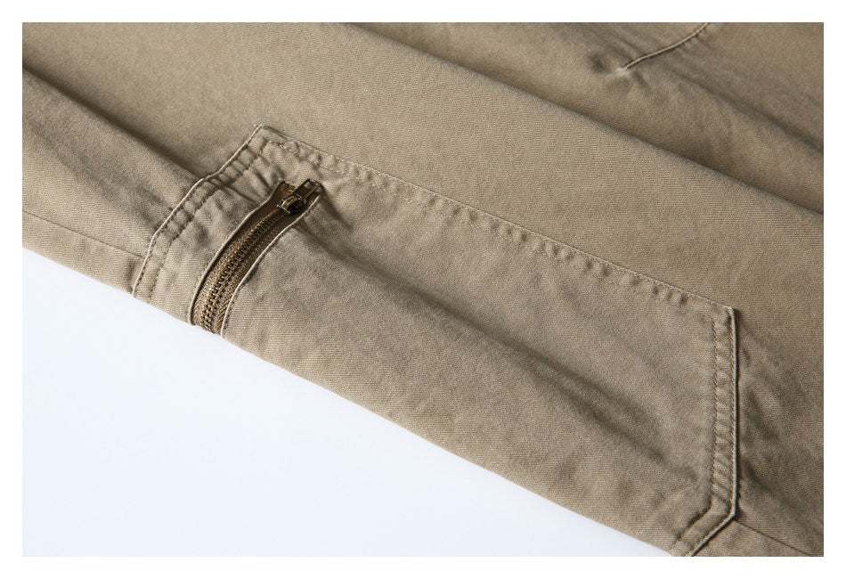 Close-up of taupe trousers with a zippered pocket and stitched pocket edges.