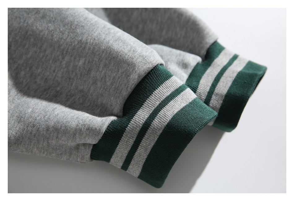 Close-up of gray sweatshirt sleeves ending in dark green ribbed cuffs with two light stripes.