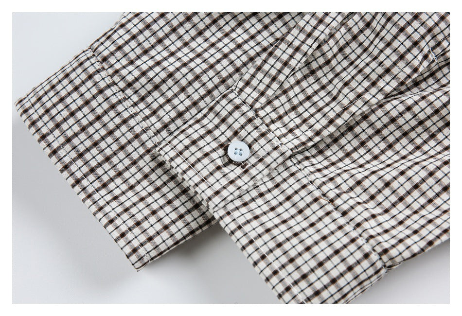 Close-up of a white button on a black-and-brown checked cuff or placket.