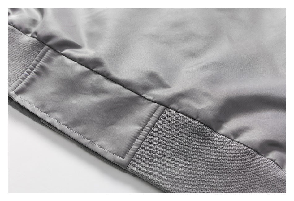 Close-up of a gray garment showing a stitched panel and wide ribbed band along the edge.